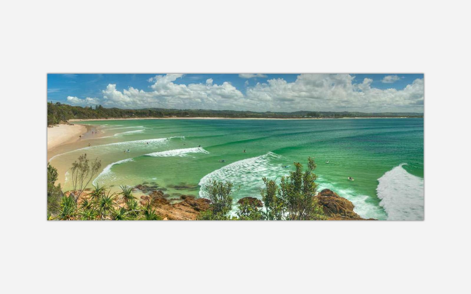 Byron-Bay A panoramic artwork depicting a vibrant beach scene with turquoise waters, white sandy beach, waves, and green coastal vegetation.