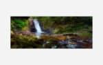 A panoramic photograph of a small serene waterfall in a lush forest setting with vibrant greens and flowing water over river rocks.