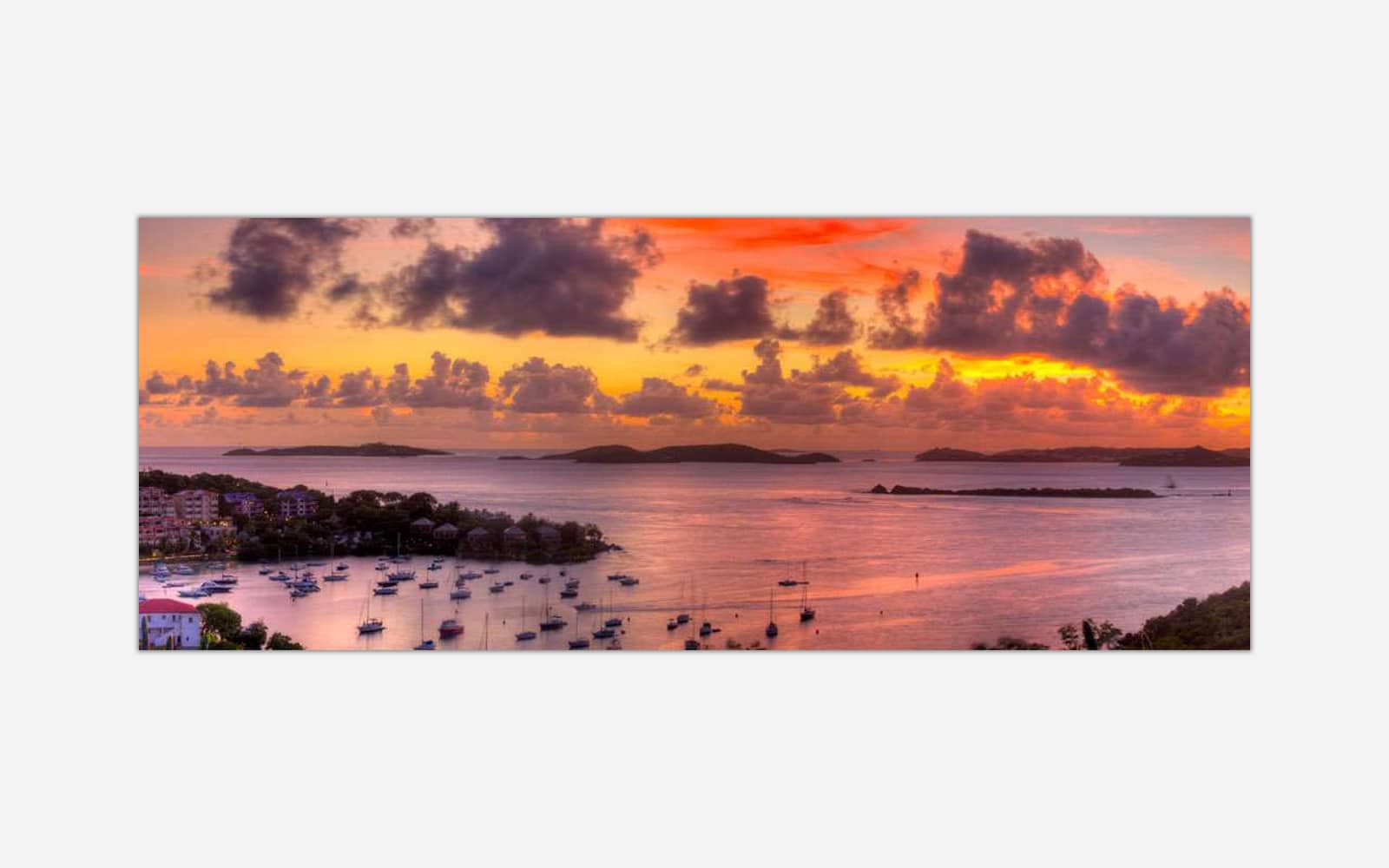 Cruz Bay (1) A vibrant painting of a sunset over a marina filled with boats, with a backdrop of islands and a colorful sky reflected in the water.