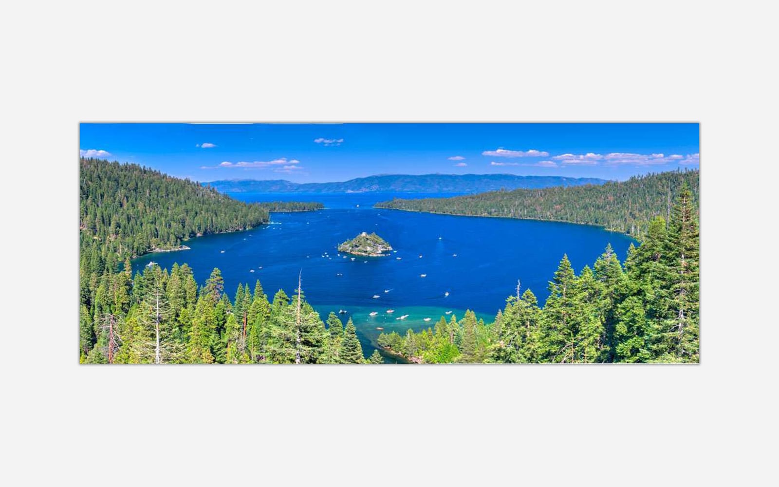 Emerald Bay (1) Panoramic view of the blue waters of Lake Tahoe with surrounding green forests and mountain ranges under a clear sky.