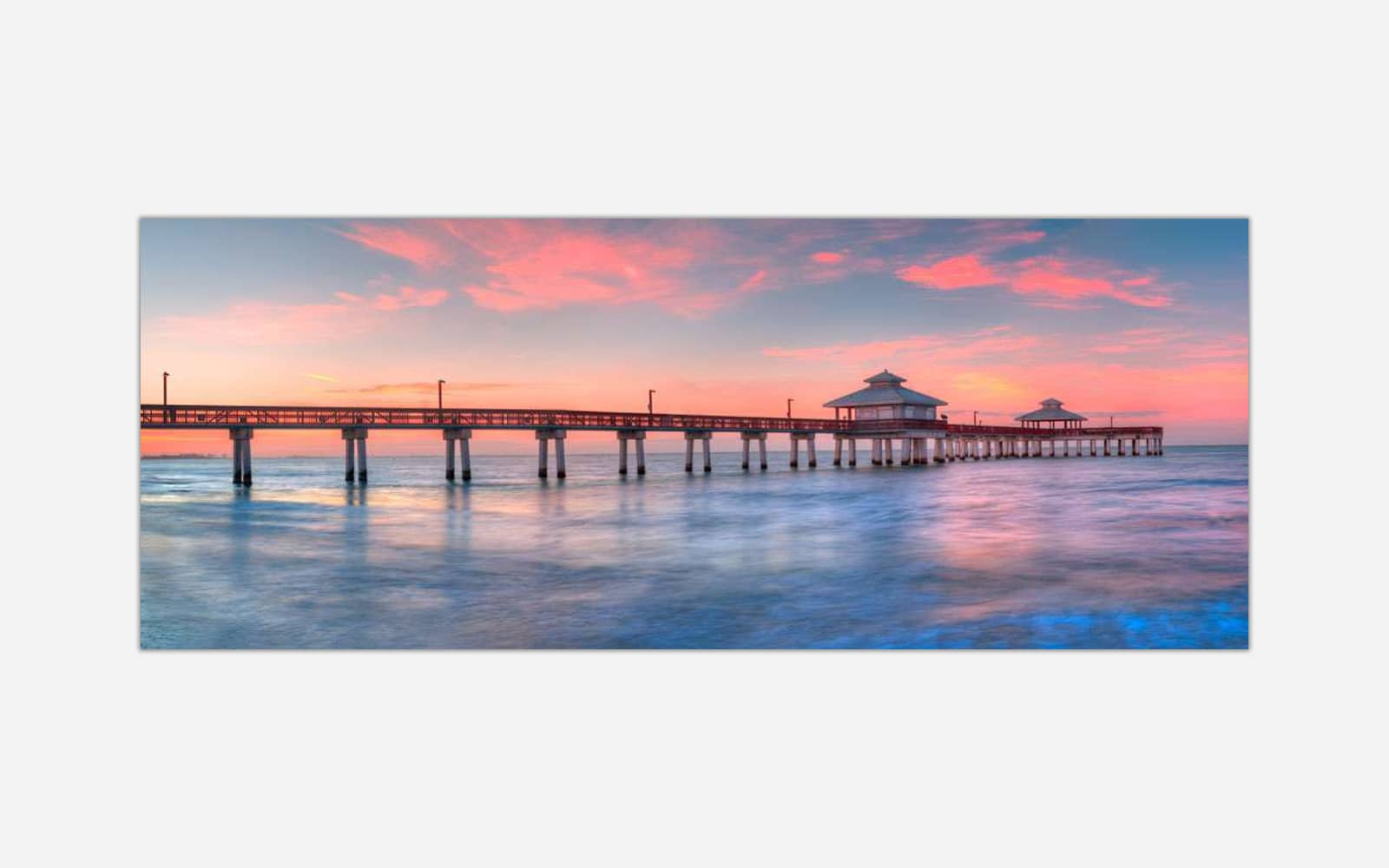 Ft. Myers (1) A serene image of a long pier extending into calm waters under a pastel-colored sunset sky.