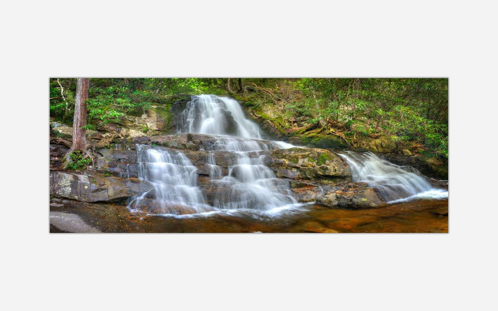 Laurel Falls (1) A photograph of a small, serene waterfall with silky smooth water cascading over rocks in a lush forest setting.