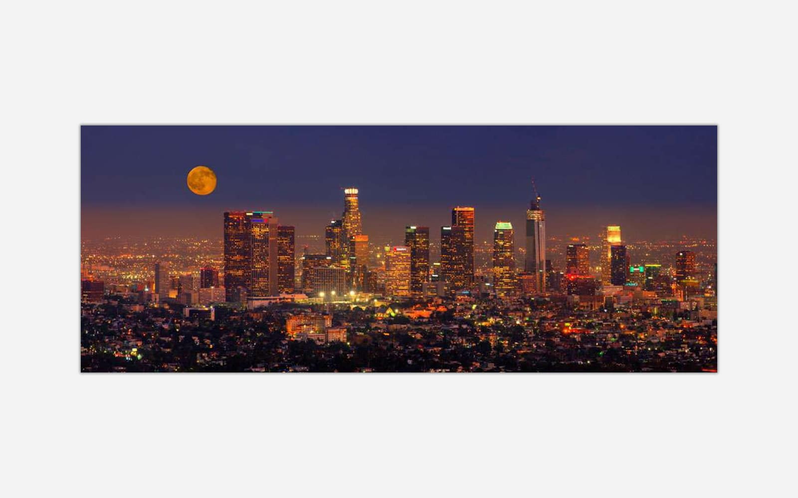 Los Angeles (1) A panoramic view of an illuminated city skyline at night with a full moon in the sky.