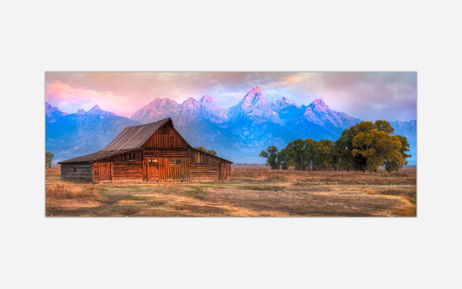 Moultons Barn 2 (1) A scenic landscape photograph featuring a rustic wooden cabin with the Grand Tetons mountain range in the background during sunset.