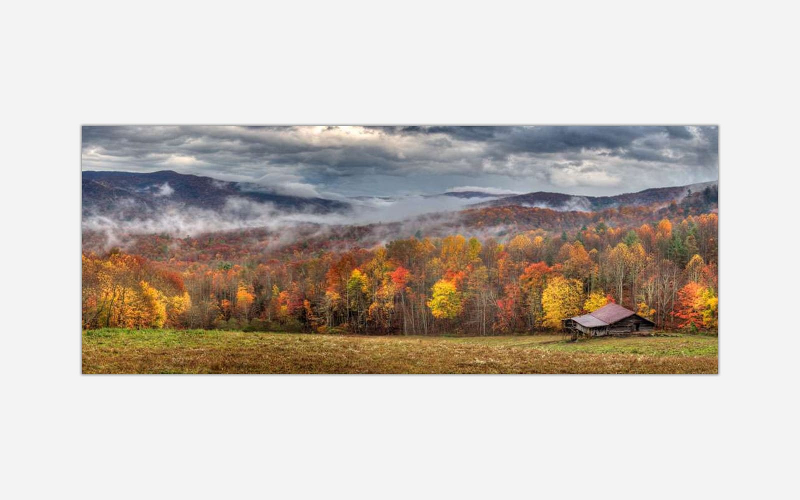 Never Grow Old (1) A panoramic photograph of a rustic cabin amidst a colorful autumn forest with misty mountains in the background.