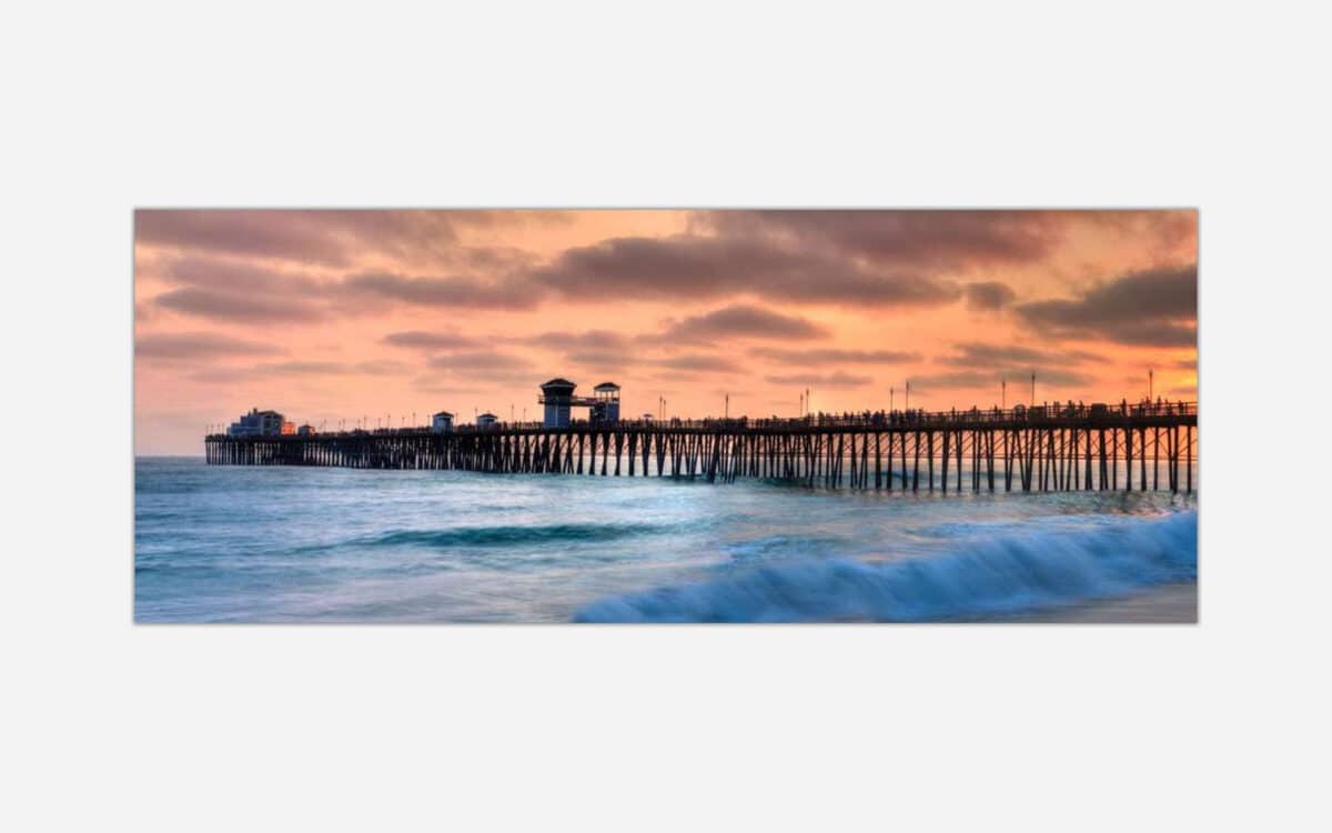 A serene sunset over a wooden ocean pier with vibrant sky colors and a calm sea.