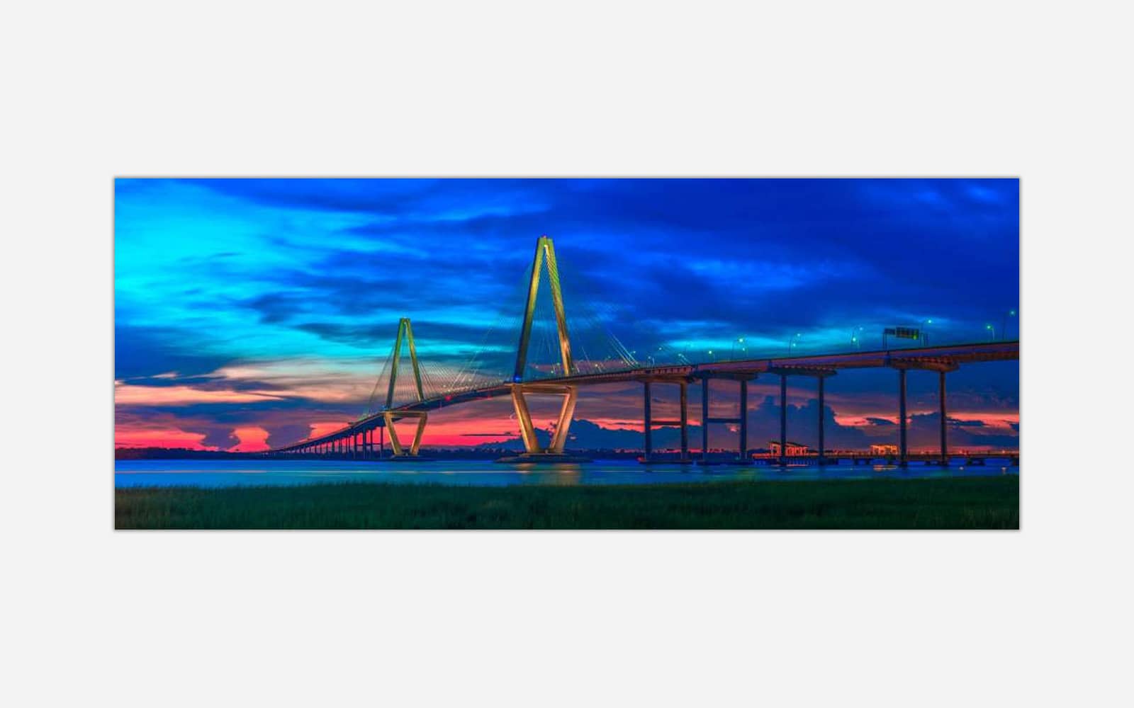 Ravenel Bridge (1) A panoramic photograph of a suspension bridge at dusk with a vibrant and colorful sky in the background.