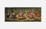 Panoramic photograph of a collection of old, rusty vintage trucks abandoned in a forest clearing.