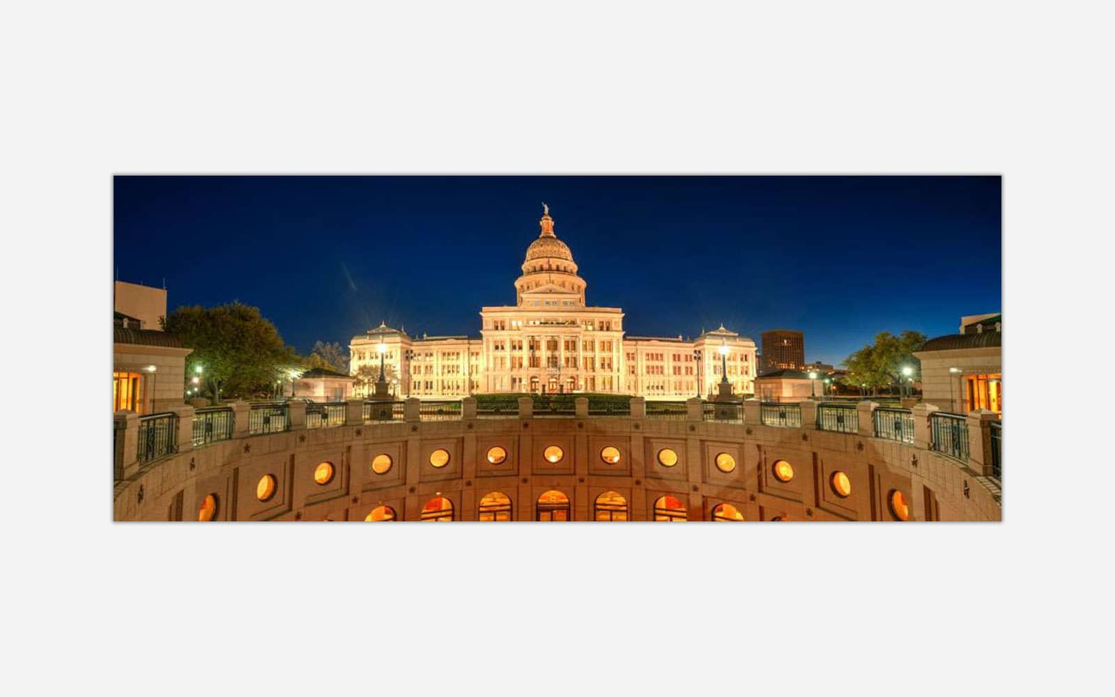 Texas State Capitol (1) A nighttime view of a grand state capitol building with illuminated windows, surrounded by a cityscape under a twilight sky.