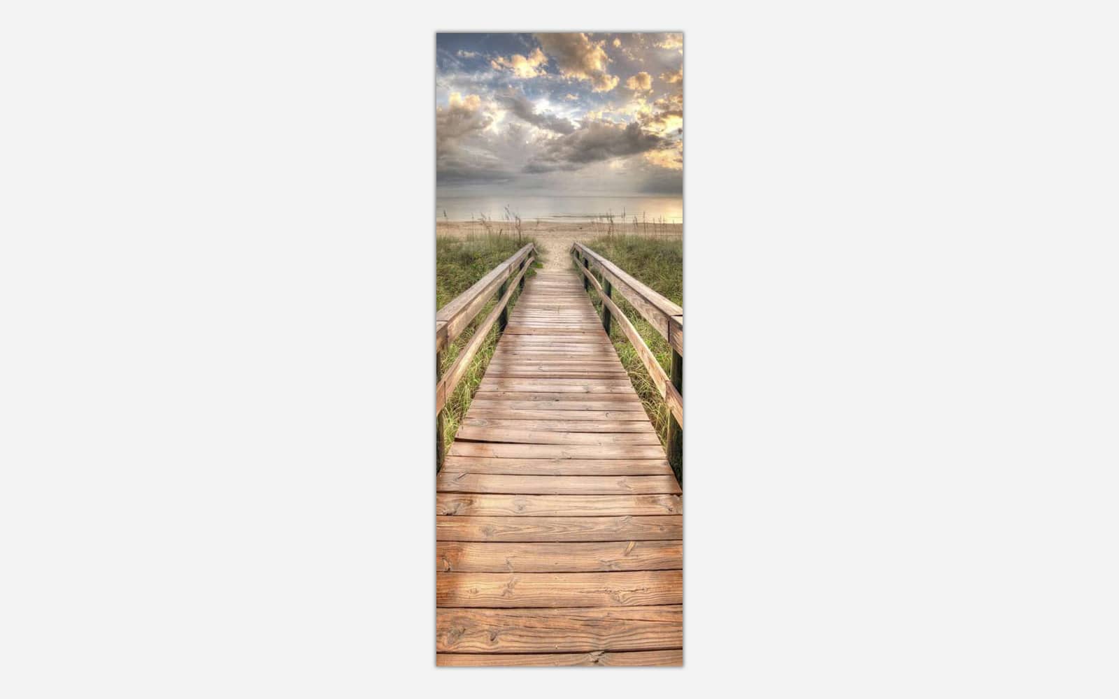 Walk This Way A vertical photograph of a wooden boardwalk leading through beach grass towards the ocean with a cloudy sky at sunset.